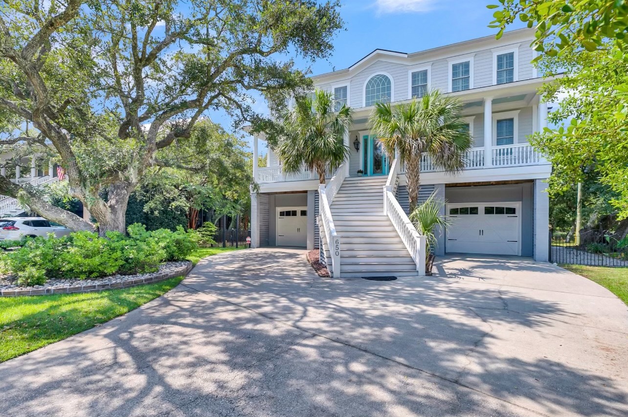 Two-story Charleston home with white staircase, palm trees, and freshly painted gray siding